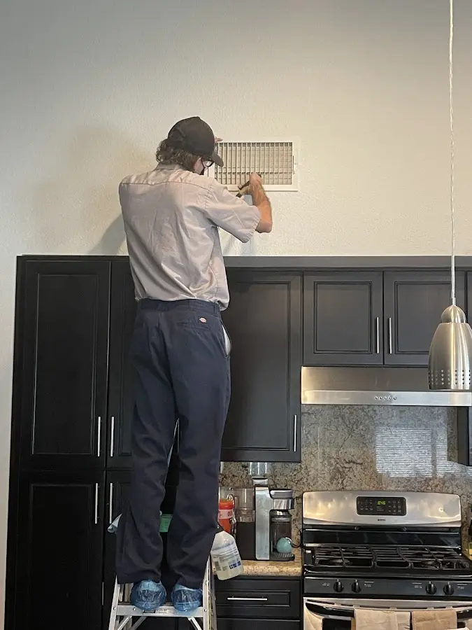 Technician inspecting an air vent during HVAC service in Clarksburg